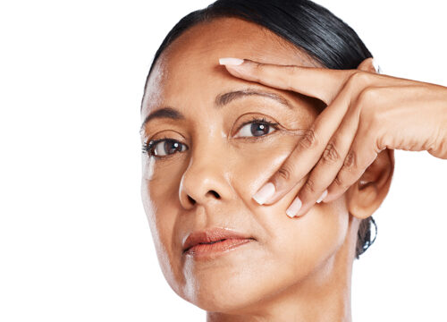 Photo of a middle age woman stretching the skin around her eyes to smooth out facial wrinkles